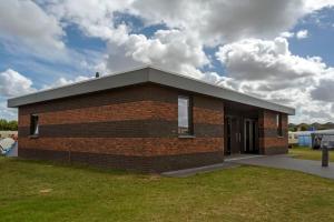 een bakstenen gebouw met een dak op het gras bij Strandcamping Jagtveld in 's-Gravenzande