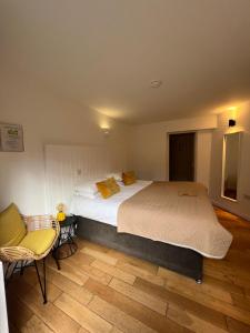 a bedroom with a large bed and a chair at Cottage Lodge Hotel in Brockenhurst