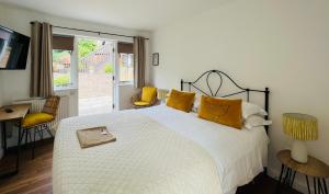 a bedroom with a large white bed with yellow pillows at Cottage Lodge Hotel in Brockenhurst