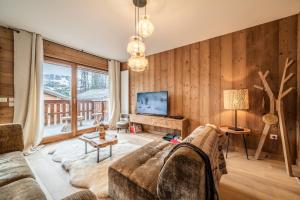 uma sala de estar com um sofá e uma grande janela em Apartment Centaurea Megève - BY EMERALD STAY em Megève