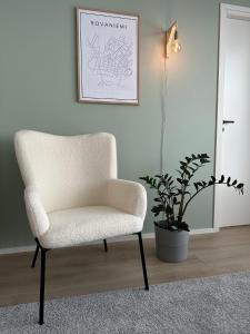 a white chair in a room with a potted plant at Brand New! Villa Moon in Rovaniemi
