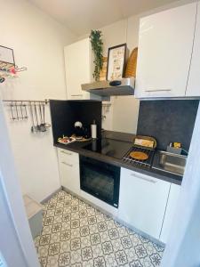 a kitchen with white cabinets and a black counter top at Superbe appartement avec internet et parking gratuit in Avignon