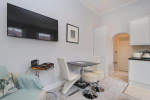 ein Wohnzimmer mit einem Tisch und einem TV an der Wand in der Unterkunft Cosy Kensington flat, 2 min to tube in London