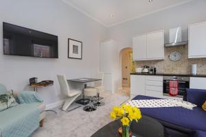 eine Küche und ein Wohnzimmer mit einem Sofa und einem Tisch in der Unterkunft Cosy Kensington flat, 2 min to tube in London