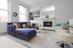 ein Wohnzimmer mit einem blauen Sofa und einem Kamin in der Unterkunft Cosy Kensington flat, 2 min to tube in London
