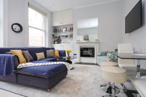 ein Wohnzimmer mit einem blauen Sofa und einem Tisch in der Unterkunft Cosy Kensington flat, 2 min to tube in London
