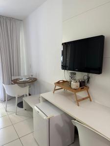a living room with a tv on a white wall at Ap. Vista pra piscina - Iloa in Barra de São Miguel