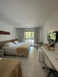 a hotel room with two beds and a flat screen tv at Ap. Vista pra piscina - Iloa in Barra de São Miguel