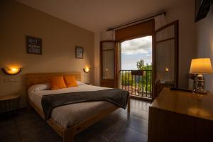 a bedroom with a bed and a balcony with a window at Hostal Montserrat in Montseny