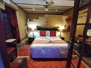 a bedroom with a large bed with red pillows at A Cherry Lane Self Catering and B&B in Bloemfontein