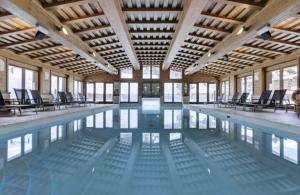 a large swimming pool with chairs in a building at ARC 1950 - Appartement 10 personnes Duplex Cheminée - ski aux pieds - Sauna, Hammam, Jacuzzi in Arc 1950