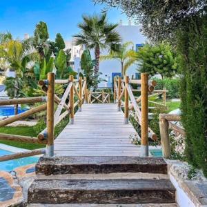 a wooden walkway leading to a beach with palm trees at 0501 Paraíso Pueblo · Amazing new Apartment - 3 bed. 51 in Estepona