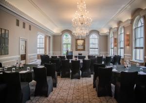 a room with tables and chairs and a chandelier at Queens Hotel Cheltenham in Cheltenham