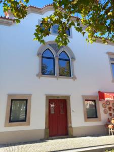 a white building with a red door and windows at CASA DA ALAMEDA in Nisa