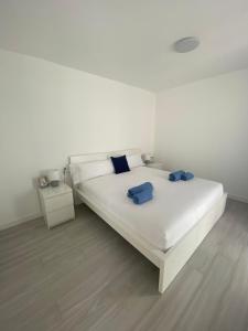 Una cama blanca con dos almohadas azules. en Villa Sol Fuerteventura, en La Oliva
