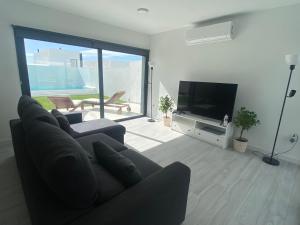 sala de estar con sofá y TV de pantalla plana en Villa Sol Fuerteventura, en La Oliva