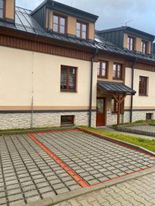 a house with a cobblestone driveway in front of a building at Apartmán v Kašperských Horách in Kašperské Hory