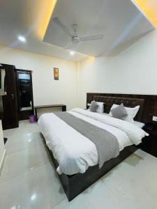 een slaapkamer met een groot bed met witte lakens bij Divine Ganga by MJ Hospitality in Haridwār