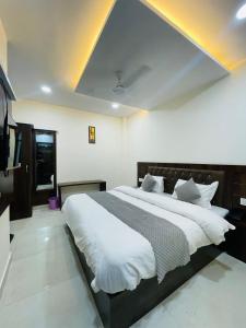 a bedroom with a large bed with white sheets at Divine Ganga by MJ Hospitality in Haridwār