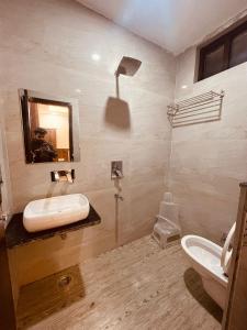 een badkamer met een wastafel, een toilet en een spiegel bij Divine Ganga by MJ Hospitality in Haridwār