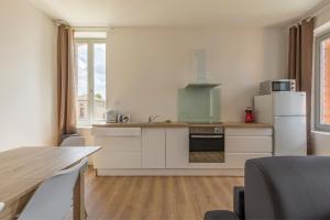 a kitchen with white cabinets and a refrigerator and a table at ABEILLE - 2 chambres et 1 canapé-lit, 1er étage, parking in Castelsarrasin