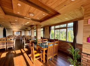 大吉嶺的住宿－Darjeeling Hillside Inn，用餐室配有木桌和椅子