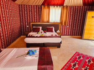 a bedroom with two beds and a table with flowers at Harir Rum luxury camp in Wadi Rum