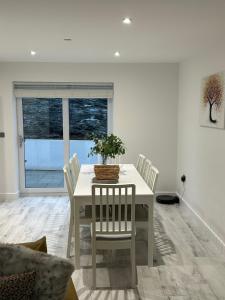 a white dining room with a table and chairs at Garreg Fawr Trearddur Bay - Ty Melyn in Trearddur
