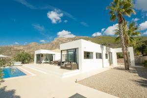 une maison blanche avec un palmier et une piscine dans l'établissement Hill house Spain -villa casa blanca, à Almuñécar