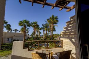 a balcony with chairs and palm trees at Hurghada Coral Beach Hotel in Hurghada