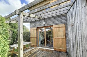 un edificio de madera con un banco en la cubierta en Les Rêves du Crotoy, en Le Crotoy