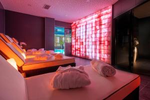two beds in a room with pink lighting and towels at PLAZA Premium Darmstadt in Darmstadt