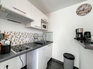 a kitchen with white cabinets and a clock on the wall at Les Rêves du Crotoy in Le Crotoy +2 photos
