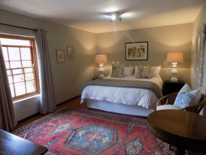 Schlafzimmer mit einem Bett, einem Tisch und einem Fenster in der Unterkunft Barrydale Karoo Lodge - Boutique Hotel in Barrydale