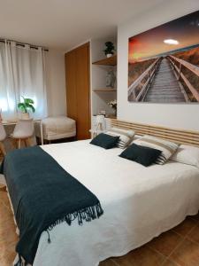 a bedroom with a large bed with a painting on the wall at Estudios El Quijote in Alcalá de Henares