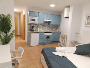 a room with a bed and a kitchen with blue cabinets at Estudios El Quijote in Alcalá de Henares