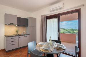 une cuisine et une salle à manger avec une table et des chaises dans l'établissement Residence Rocce Rosse, à Isola Rossa 58 autres photos