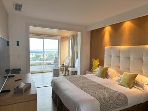 カルヴィにあるHotel Revellata & Spaの大きなベッドとデスクが備わるホテルルームです。