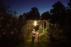 un hombre y una mujer de pie en un jardín por la noche en Boutique Hotel - Poggio ai Santi en San Vincenzo