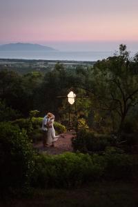 a bride and groom kissing in the forest at sunset at Boutique Hotel - Poggio ai Santi in San Vincenzo
