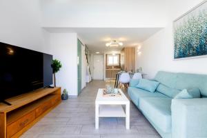 ein Wohnzimmer mit einem blauen Sofa und einem Fernseher in der Unterkunft Luxury Parque Santiago I in Playa de las Americas