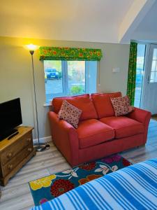 een woonkamer met een rode bank en een televisie bij Pentre Cerrig Country House in Llanferres