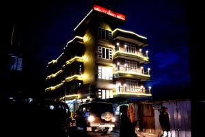 un grand bâtiment avec un panneau sur lui la nuit dans l'établissement LILY GUEST HOUSE, à Shillong