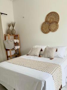 Schlafzimmer mit einem Bett mit weißer Bettwäsche und Kissen in der Unterkunft Casa Encanto das Dunas in Santo Amaro
