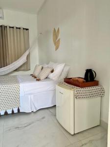 a white bedroom with a bed and a table at Casa Encanto das Dunas in Santo Amaro