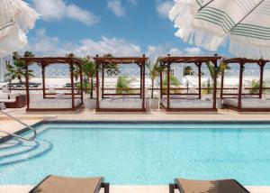 Parguera Plaza Hotel - Adults Only في لا بارغيرا: مسبح مع كراسي ومظلات