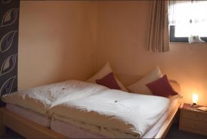 Una cama con sábanas blancas y almohadas en un dormitorio en Ferienwohnung Martina, en Medebach