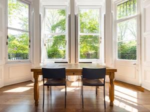 a dining room with a wooden table and chairs in front of windows at Pass the Keys Gorgeous studio with access to a private garden in London