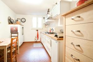 a kitchen with white cabinets and a wooden floor at B&B Mama Rò in Cesena