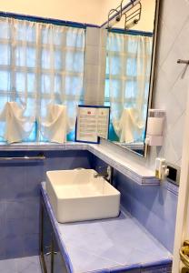 bagno con lavandino bianco e specchio di Salotto Napoletano 381 a Napoli